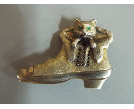 A white metal mourning brooch, depicting cat coming out of boot with green stone set eyes marked verso with kite mark, marked