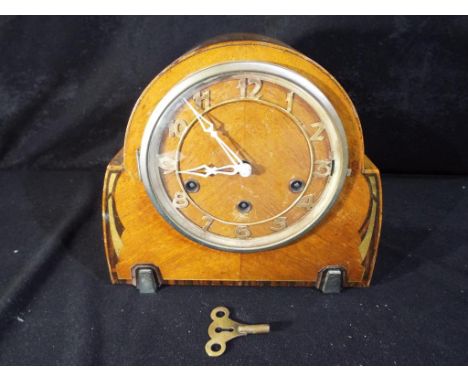 A mantle clock with Arabic numerals to the dial.An Art Deco styled Westminster chiming mantel clock, mahogany case with decor