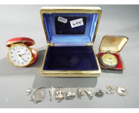 Nine white metal and silver charms, a 1902 farthing coin set in a white metal mount, a Coral travel alarm clock and a Westclo