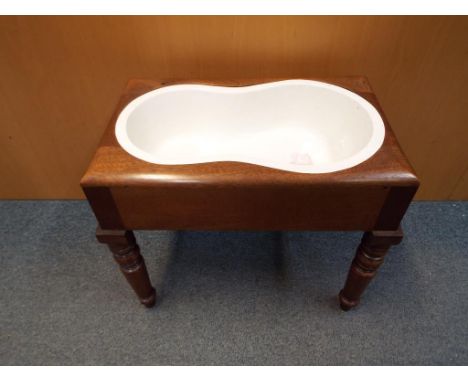 A late 19th century baby bath or commode, porcelain kidney shaped bowl inset into a mahogany stool upon turned legs with a cl