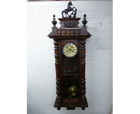 A WALNUT CASED VIENNA STYLE WALL CLOCK, the pendulum driven movement set behind an enamel dial with Roman numerals, the case 