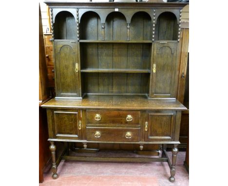 AN EARLY 20th CENTURY POLISHED DRESSER, the rack having two centre shelves with triple arch hooded top and shelf and cupboard