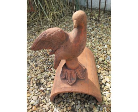 A terracotta dove roof tile ridge finial depicting a dove looking forward - 24cm H x 39cm W 