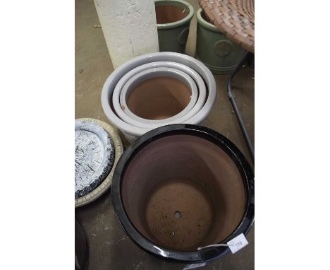 GRADUATED SET OF THREE PLANT POTS DECORATED WITH BEES, TOGETHER WITH BLACK GLAZED PLANTER AND ACCOMPANYING TRAYS
