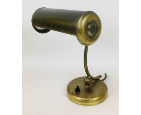 A vintage brass desk lamp, with cylindrical shade, on a circular base with press button, 19 by 26cm high. 