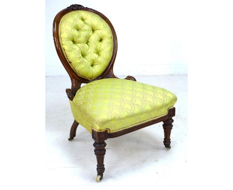 A Victorian mahogany spoon back nursing chair, with floral carved and moulded frame, upholstered in yellow satin with button 