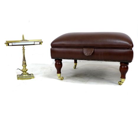 A modern leather covered Ottoman, of square form covered in brown leather and raised on turned baluster legs and brass castor