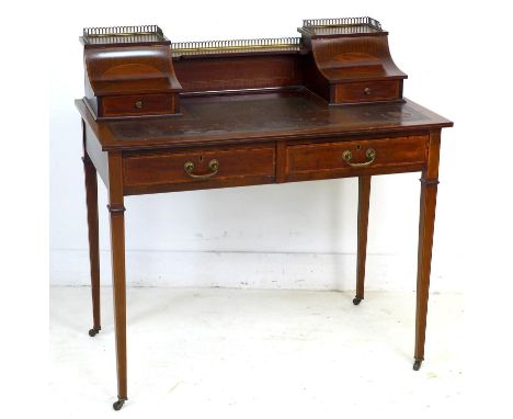 An Edwardian mahogany and line inlaid lady's writing desk, brass gallery and shelf between two concave compartments, each wit