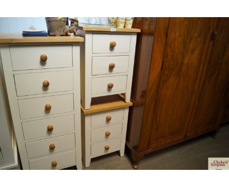 A pair of light oak topped bedside chests fitted three drawers