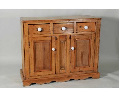 A rustic country pine kitchen cupboard with a trio of drawers above a pair of hinged panelled cupboard doors flanking a fixed
