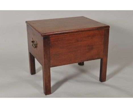 A heavy 19 th century mahogany commode, of solid planked construction, the hinged cover revealing a vacant interior, flanked 