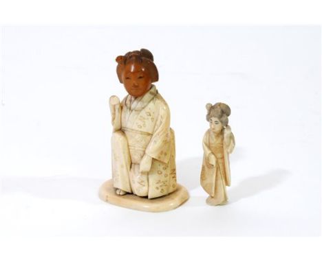 A Japanese carved and stained bone okimono of a geisha, Meiji period, she half kneels with her right arm raised and wearing t