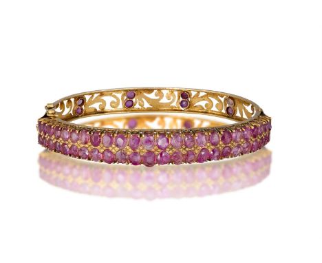 A LATE 19TH CENTURY RUBY BANGLE Of openwork design, the frontispiece set with two rows of graduated old cushion-shaped rubies