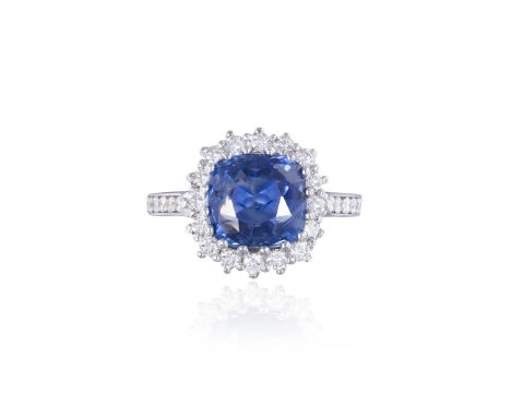 A SAPPHIRE AND DIAMOND CLUSTER RINGThe cushion-shaped sapphire, weighing 6.06cts, within a multi-claw setting, to a brilliant