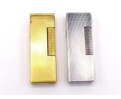 DUNHILL, a gilt metal lighter, of engine turned design, 6.4cm long, together with a white metal example (2) CONDITION: the fi