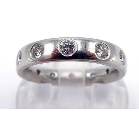 A platinum and diamond eternity band by Garrard & Co, the band rub over set at intervals with twelve small brilliants totalli