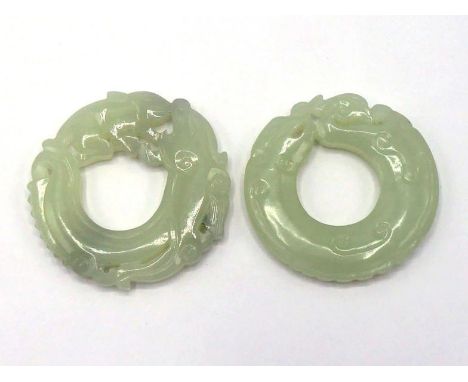 Two Chinese carved white jade circular plaques, one depicting a dragon and phoenix head to head, coiled as a circle; the othe
