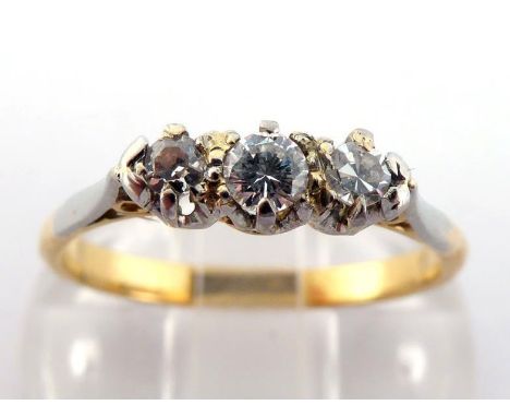 A three stone diamond ring, set with an approx. 0.10 carat central brilliant between two single cuts, the shank stamped '18CT