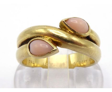 VAN CLEEF & ARPELS, A French 18 carat gold and coral ring, the pear shaped peau d'ange cabochons rub over set as terminals to