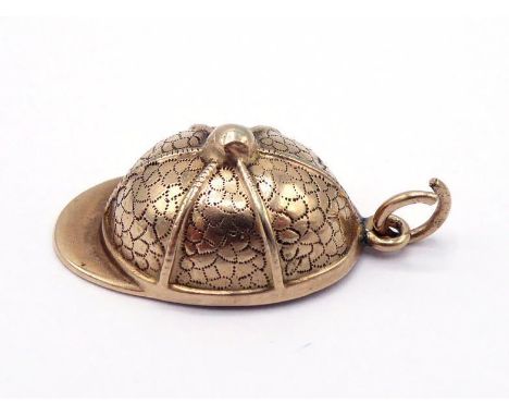 A yellow metal (tests 12 carat gold) charm, in the form a jockey's cap, with compass to the interior, 2cm long, 2.6gms CONDIT