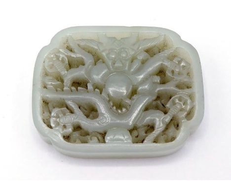 A Chinese carved white jade dragon plaque of rectangular form with incurved corners, back ground level pierced with scrolling