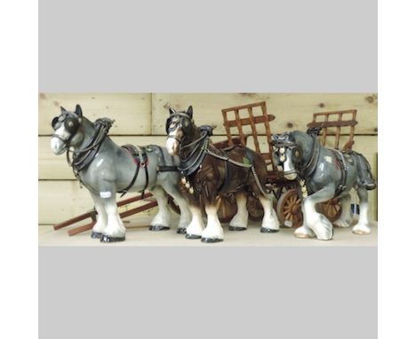 A collection of pottery models of carthorses, together with two model caravans