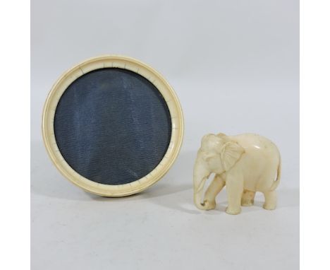 An early 20th century ivory circular photograph frame, 14cm diameter, together with a model of an elephant