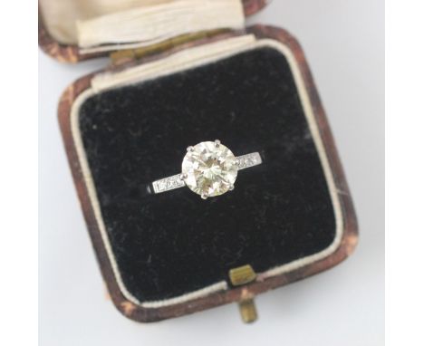 A mid 20th century diamond solitaire ring, the central round cut diamond with a trio of diamonds set to the shoulders, within