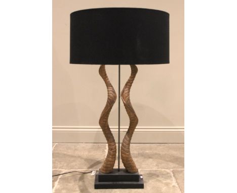 An antelope antler table lamp, the two symmetrically twisted antlers enclosing a central light fitting, upon a plinth base, 1