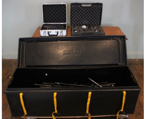A large selection of microphone stands, including black boom mike stands, speaker poles, within heavy duty travel hard case o