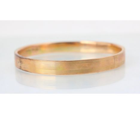 A 9ct yellow gold bangle, the hollow bangle with engine turned detail to exterior, 8cm wide, 14gms 