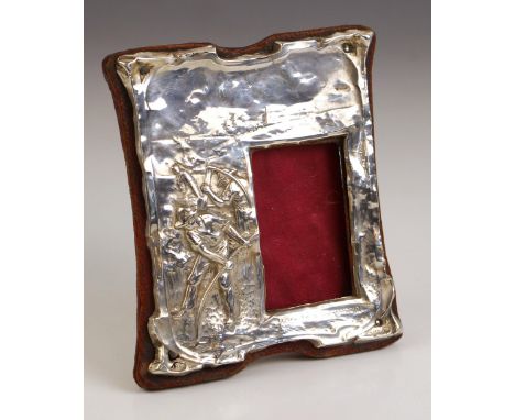 An Edwardian silver photograph frame, possibly George Houston, Birmingham 1905, the shaped frame with embossed depiction of f