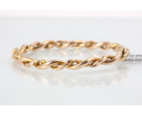 A gold coloured bangle, the rope twist bangle with box and tongue fastening, unmarked, 13gms (at fault) 