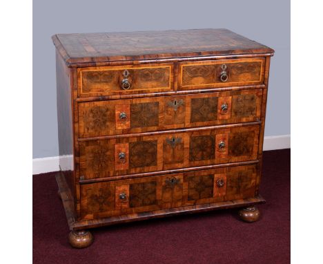 An antique oyster veneered chest fitted with two short and three long drawers on bun feet with ring drop handles and brass es
