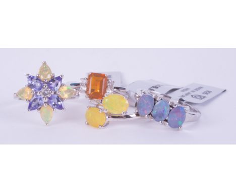 Four silver rings to include a three stone Boulder Opal set ring, a two stone crossover style ring set with yellow Ethiopian 