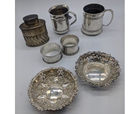 A collection of silver items to include 2 mugs, a tea caddy, 2 napkin rings, 2 bonbon dishes, British hallmarks, total weight