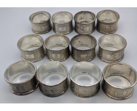 A set of 12 silver napkins rings, engine turned outers, hallmarked Birmingham, 1957, maker C&amp;N, 425g