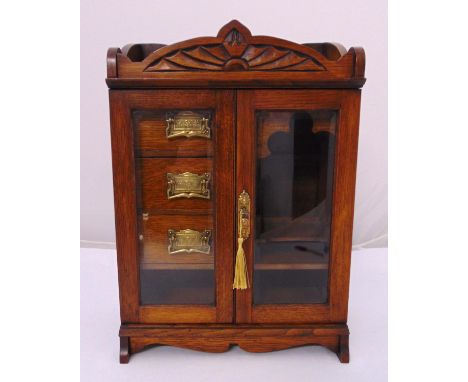 An Edwardian rectangular oak cased smokers cabinet, three drawers with brass handles and two hinged glazed doors all on brack