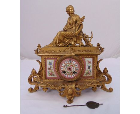 A 19th century French gilt metal mantel clock with porcelain panels surmounted by a female figure on four leaf chased scroll 