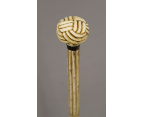 A 19th century carved whalebone walking stick with carved ivory sailors knot handle. 89 cm long.