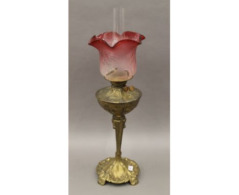 An Art Nouveau style brass lamp with red etched shade. 72 cm high overall.