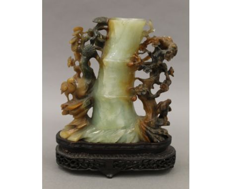 A Chinese carved jade brush pot mounted on a carved wooden stand. 20 cm high overall.