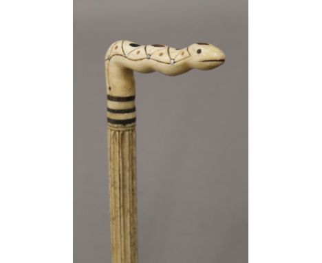 A 19th century carved whalebone walking stick with carved ivory snake form handle. 85.5 cm long.