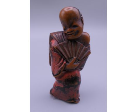A Japanese carved wooden netsuke formed as a man holding a fan. 5.25 cm high. 