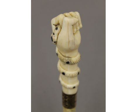 A 19th century whalebone walking stick with carved ivory clenched fist and snake handle, with a gold plated collar. 84 cm lon