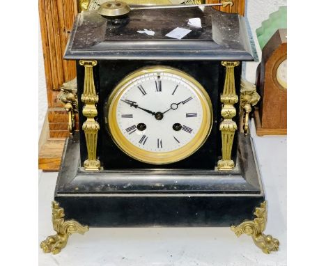 A slate chiming mantel clock with fine brass detailing in the form of brass lions head handles to the side on brass lions fee
