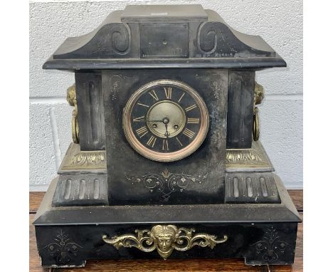A slate mantel clock with mask handles and gilded frieze