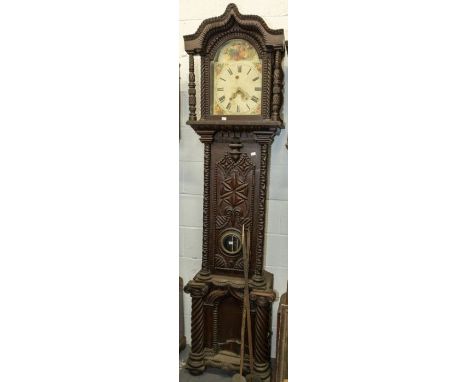 A heavily carved dark long case clock with painted dial decorated with flowers and fruit. Decorative carving to hood, door wi