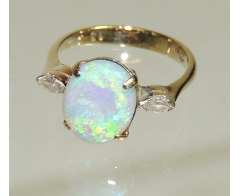 A 14ct gold opal and diamond ladies ring, set with a central oval cabouchon opal with a marquise cut diamond to each shoulder