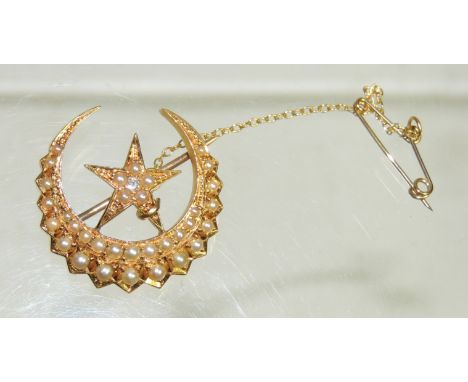 A Victorian 18ct gold star in a crescent brooch.  The star set with a central diamond and tiny seed pearl surround, the cresc